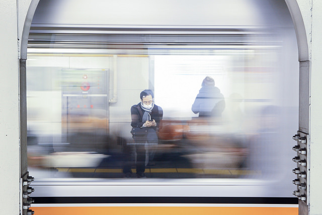 Person sitting in a station with a mobile in hand