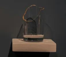 A glass that may have formerly been quite tall; its entire circumference has been cut to an uneven jagged edge.